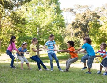 Bambini giocano a tiro alla fune in un parco.