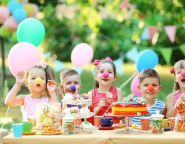 Bambini festeggiano con nasi da clown e dolci colorati.