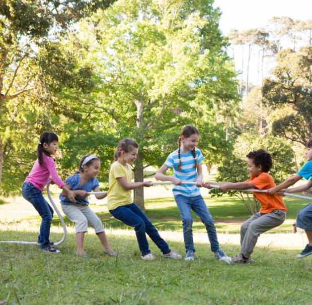 Bambini giocano a tiro alla fune in un parco.