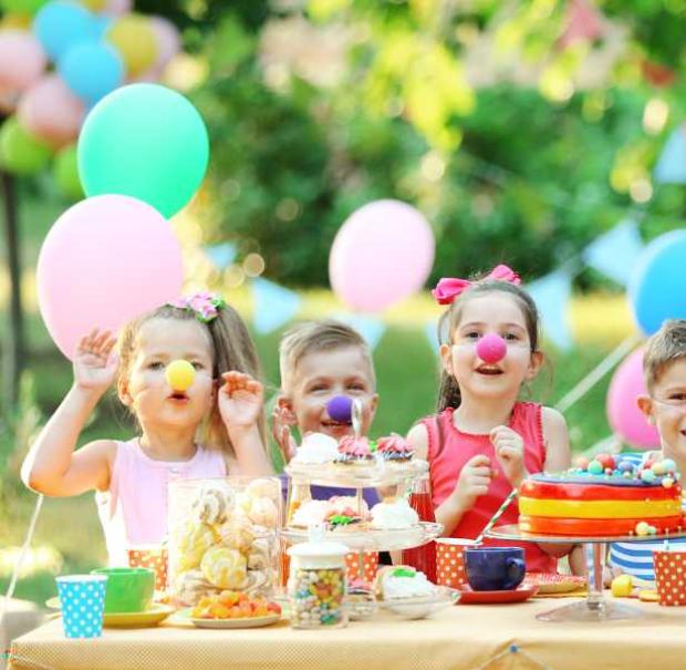 Bambini festeggiano con nasi da clown e dolci colorati.